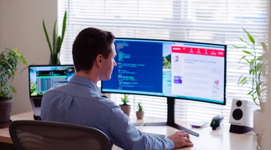 man in gray dress shirt sitting on chair in front of computer monitor